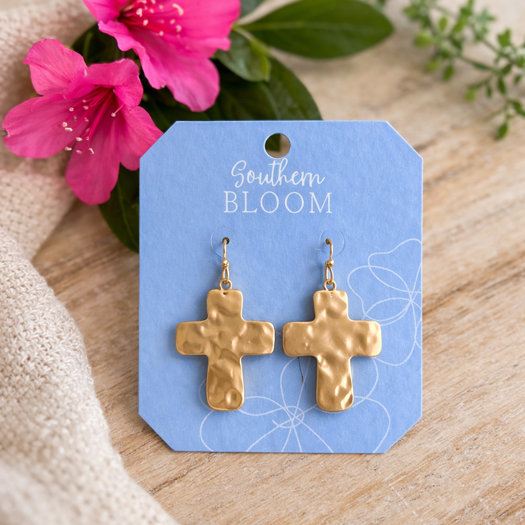 Gold cross earrings on a 'Southern Bloom' branded card with pink flowers in the background.